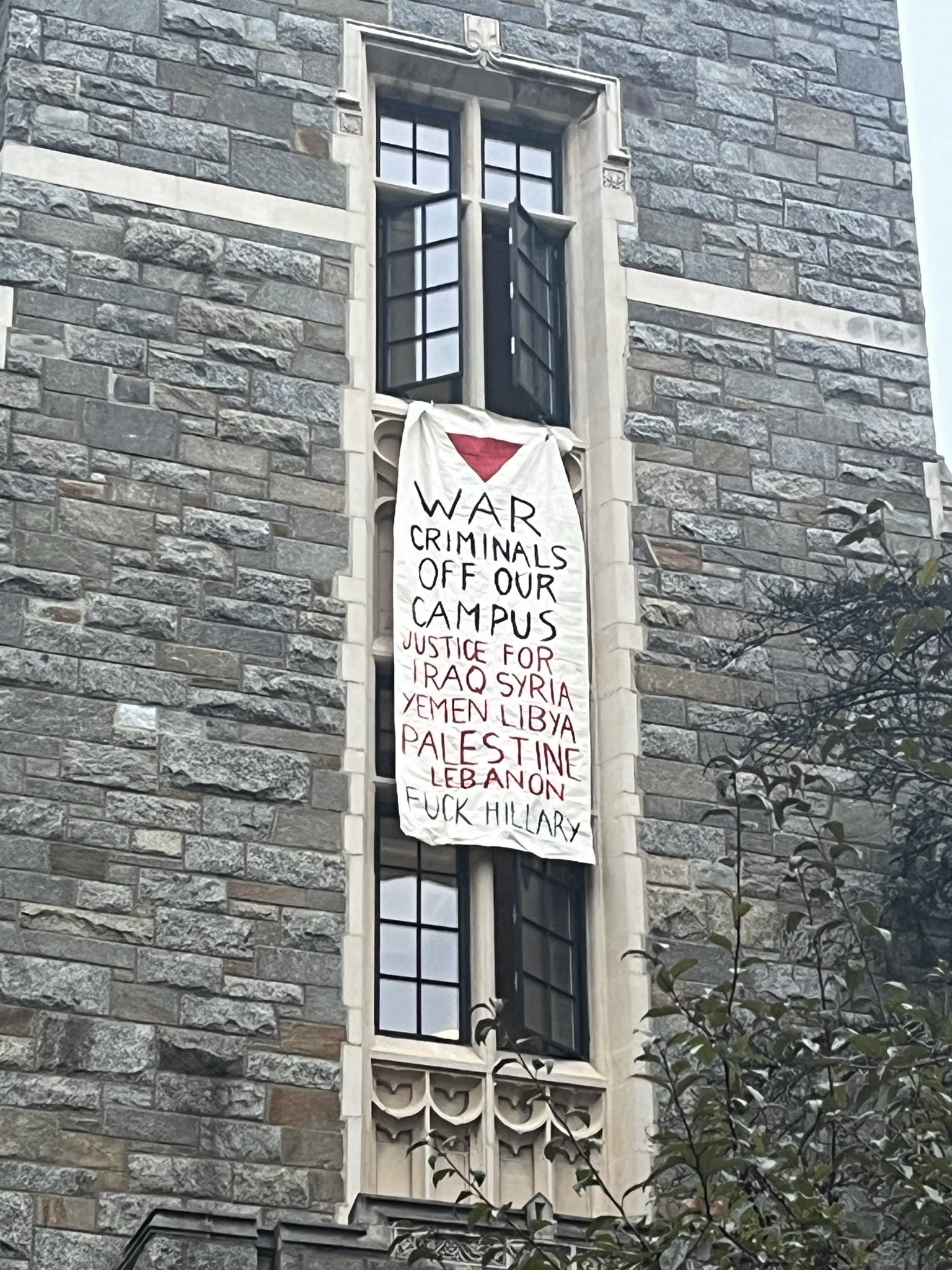 Banner hung from a window that reads: War criminals off our campus. Justice for Iraq, Syria, Yemen, Libya, Palestine, Lebanon. Fuck Hillary.