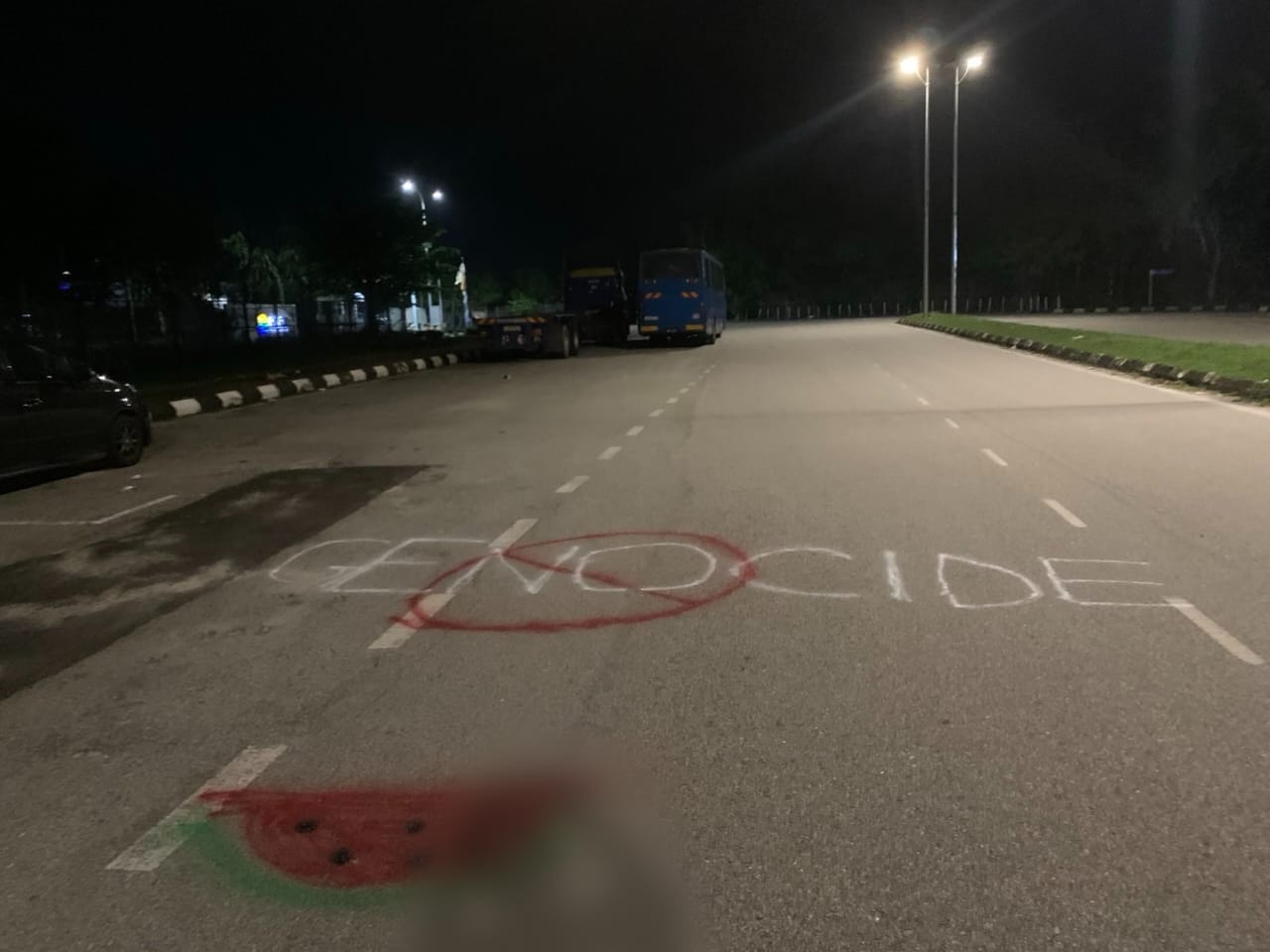 The word "Genocide" with a no symbol over it, and a watermelon below it, graffitied on a street.